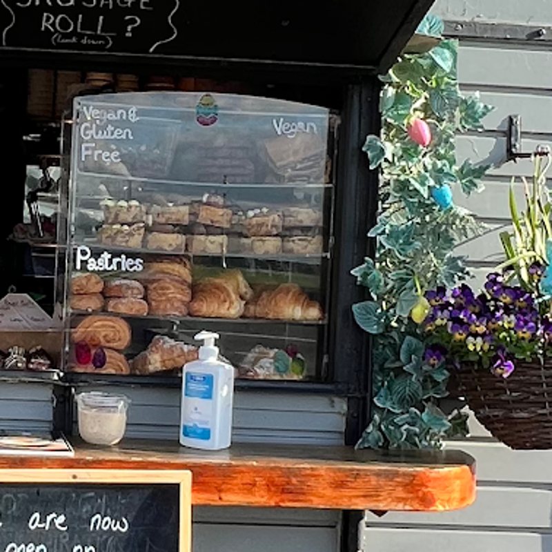 The glass case at the trailer window with pastries and a vegan and gluten-free shelf, labelled in chalk.